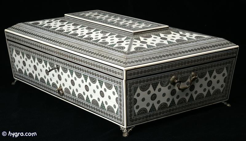  Important large Anglo Indian fully fitted sewing and writing box of pyramided shape veneered with ivory profusely inlaid with sadeli mosaic, the box having swan neck handles to the sides and standing on cast paw feet of unusual design. Inside the box is compartmentalized  with fragrant sandalwood and has supplementary lids and trays each veneered with ivory inlaid with sadeli,  circa 1845. Enlarge Picture
